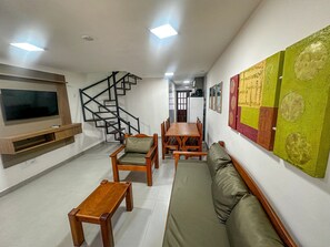 Un soggiorno con televisione, arredi in legno, una scala e un muro decorato con opere d'arte.
