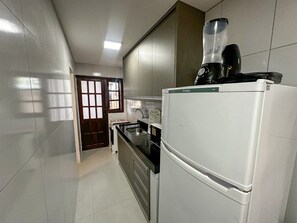 Een keuken met een koelkast, een spoelbak en een raam.