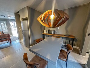 Een moderne keuken met een eettafel, stoelen en een bijzondere hanglamp.