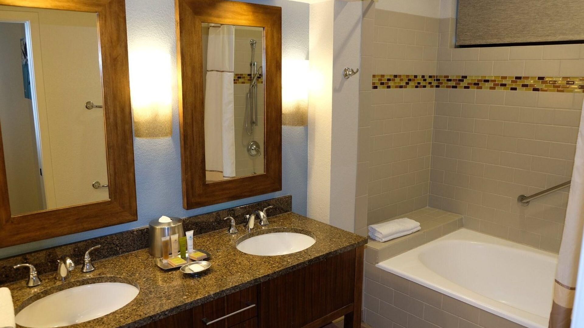 Un baño con dos lavamanos, un espejo, ducha y bañera.