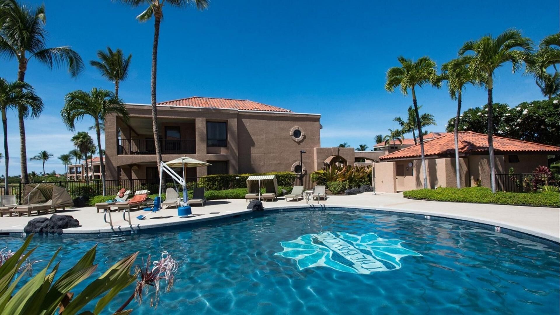 Un resort con piscina, palmeras y un edificio de techo rojo.