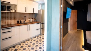 A modern kitchen with white cabinets, a wooden countertop, and a patterned backsplash. - Nichiyōbi House「UNIT #1「Koneko」 (San Juan)