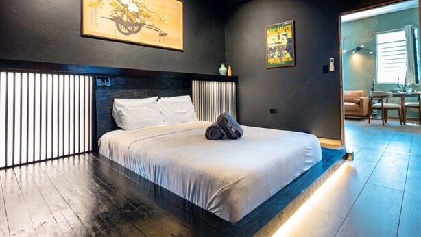 A modern bedroom with a large bed, a headboard with vertical slats, and artwork on the walls. - Nichiyōbi House「UNIT #1「Koneko」 (San Juan)