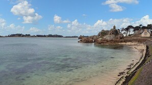 Eine Küstenlandschaft mit klarem Wasser, einem Sandstrand und Felsformationen.
