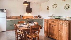 Eine Küche mit Esstisch, gedeckt für vier Personen, einer Mikrowelle, einer Kaffeemaschine und einem Schrank mit dekorativen Schnitzereien.