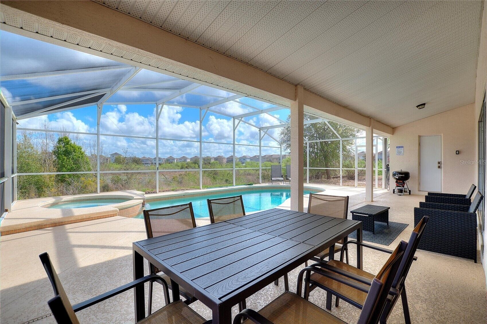 A covered outdoor area with a pool, seating, and a view of the surrounding landscape.