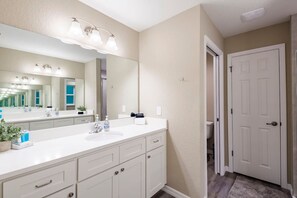 A modern bathroom with a white vanity, a large mirror, and a walk-in shower. - Springs Basecamp - 4BR Near Rainbow and Manatees (Dunnellon)