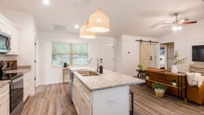 A modern kitchen with granite countertops, a central island, pendant lighting, and a ceiling fan. - Springs Basecamp - 4BR Near Rainbow and Manatees (Dunnellon)