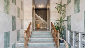 A marble staircase with wooden railings leading to a landing area with a table and chairs. - O Ninho dos Sonhos – By Y Concept (Setúbal)