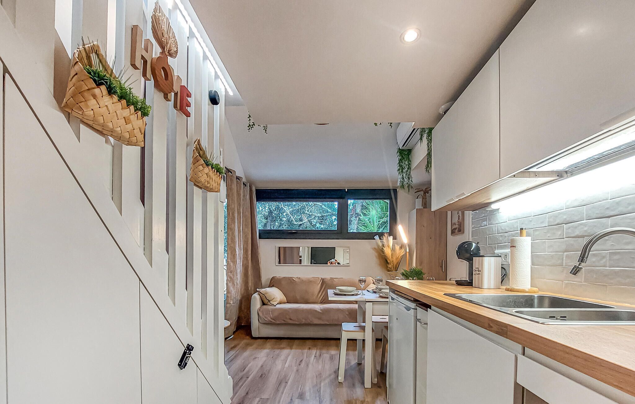A compact kitchen with a dining area, featuring a wooden countertop, a sink, and a window with a view.