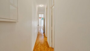 Un couloir étroit avec un plancher en bois et des murs blancs.