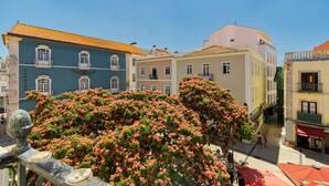 Une vue de rue avec des bâtiments, un arbre aux fleurs roses et un auvent rouge.