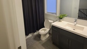 Ein modernes Badezimmer mit Toilette, Waschbecken und Dusche.