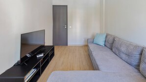 A modern living room with a flat-screen TV, a sofa, and a door. - Lisboa no Sado - By Y Concept (Setúbal)
