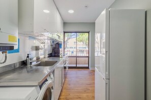 Une cuisine moderne dotée d’appareils électroménagers en acier inoxydable, d’un lave-linge encastré et d’une grande fenêtre.