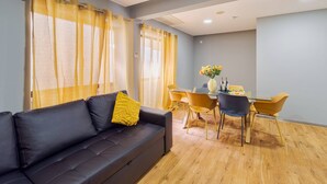Una sala de estar moderna con sofá, mesa de comedor, sillas y cortinas.