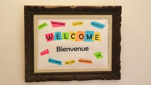 Une pancarte d’accueil encadrée, avec des messages de bienvenue dans plusieurs langues.