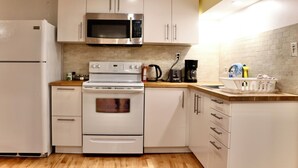Une cuisine moderne avec des meubles blancs, un four à micro-ondes en acier inoxydable, une cuisinière blanche et un plan de travail en bois.