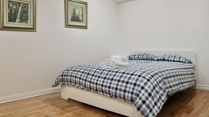 Une chambre à coucher avec un lit, des murs blancs et deux tableaux encadrés accrochés au mur.
