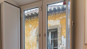 Quarto com porta de vidro deslizante que dá para uma varanda com grades de metal.