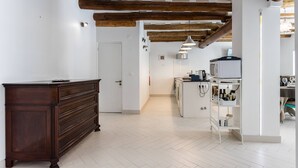 Eine geräumige Küche mit Holzbalken, einem weißen Kühlschrank und einem weißen Schrank mit Regalen.