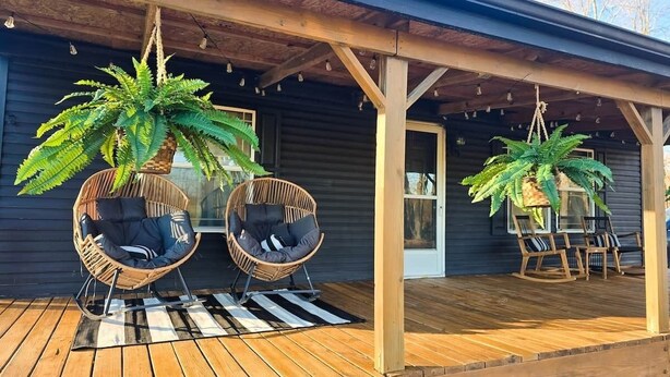 A wooden deck with two wicker chairs and a potted plant.