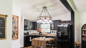 A modern kitchen with a central island, black cabinetry, and a hanging light fixture.