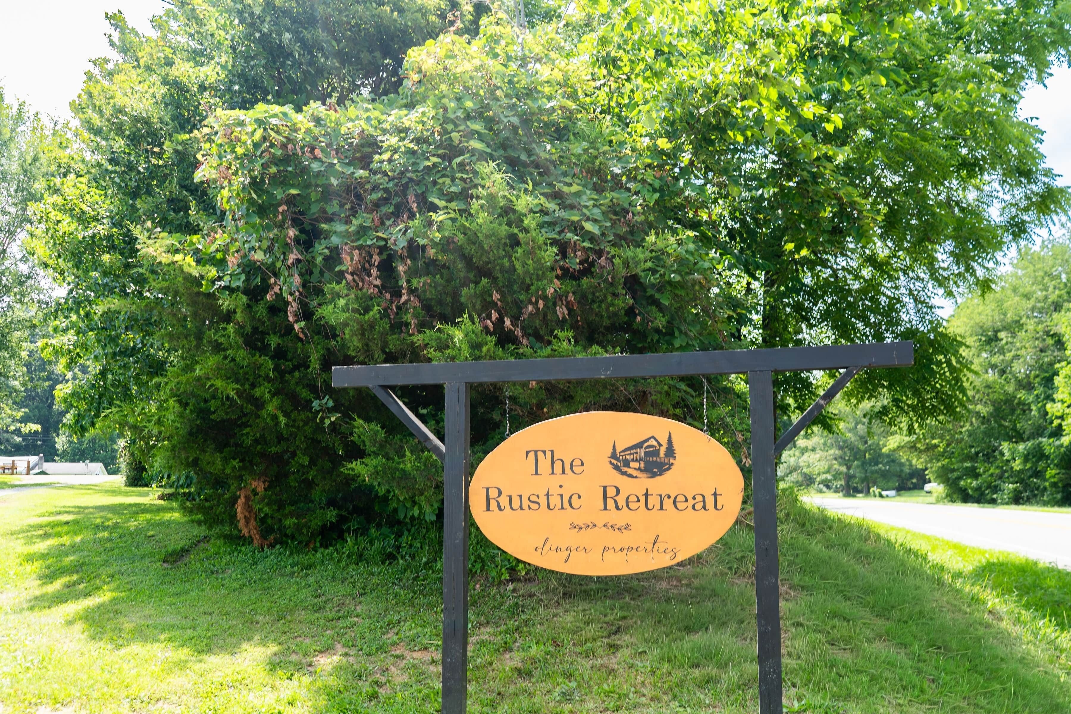 Un letrero para The Rustic Retreat con un logotipo de una cabaña y el texto 'Colinger properties'.