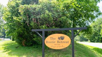 Un letrero para The Rustic Retreat con un logotipo de una cabaña y el texto 'Colinger properties'.