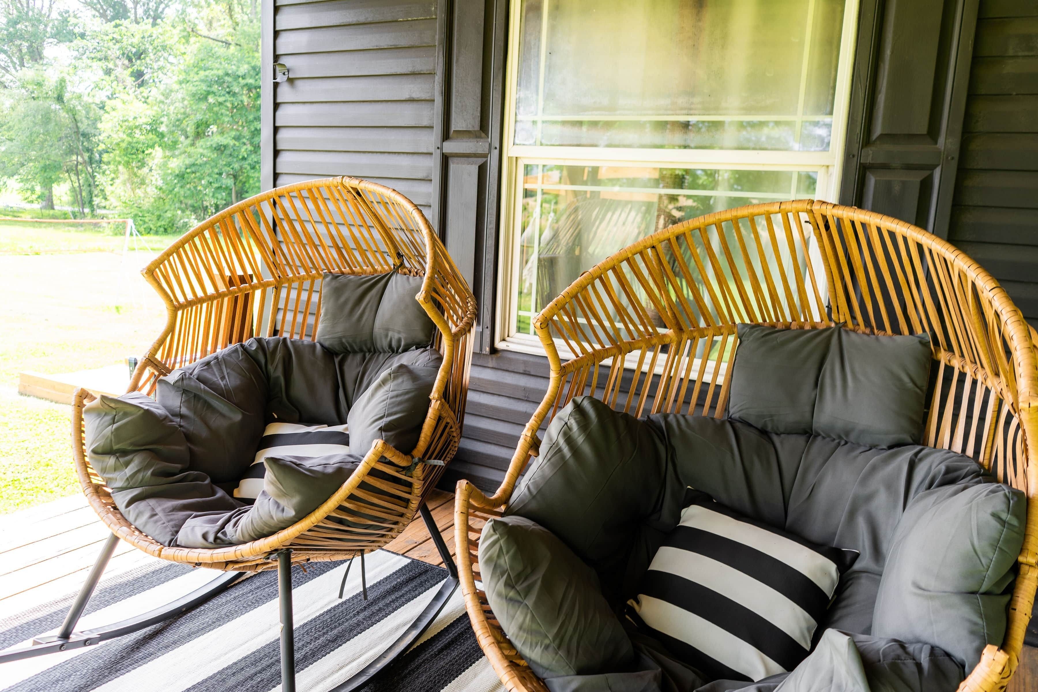 Zwei Korbstühle mit Kissen auf einer Veranda.