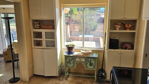 A compact kitchen with white cabinets, a small dining table, and a window with a view of the outdoors. - Beautiful 2-bedroom Golf house in Green Valley perfect for relaxing getaway (Green Valley)