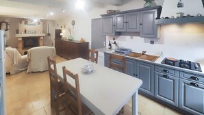 Une cuisine compacte avec des meubles gris, une table à manger avec des chaises et une cuisinière encastrée.