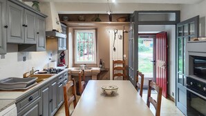 Une cuisine équipée d’une table à manger, de chaises, d’une cuisinière, de placards et d’un réfrigérateur.