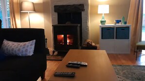 Una sala de estar acogedora con chimenea, un sofá, una mesa de centro y un mueble con objetos decorativos.