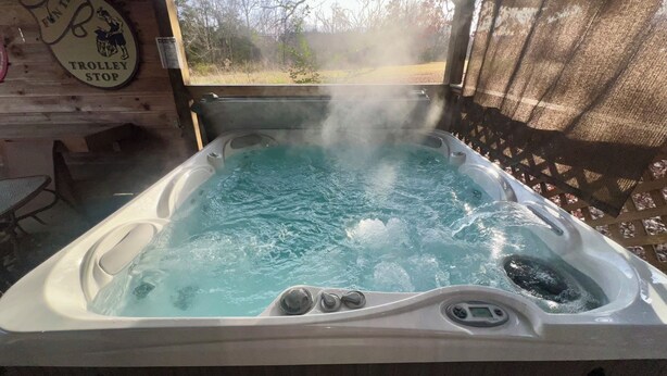 Ein Whirlpool mit aufsteigendem Dampf, eine Holzterrasse und ein Schild mit der Aufschrift 'TROLLEY STOP'.