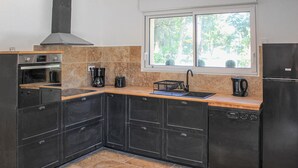 A compact kitchen with dark cabinetry, a built-in oven, a coffee maker, and a sink. - Nice home in Grignan with private swimming pool, can be inside or outside (Grignan)
