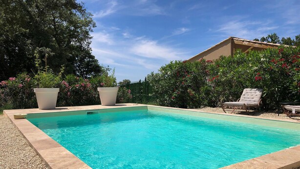 A rectangular swimming pool with clear blue water, surrounded by a pebble border. There are two white planters and a lounge chair visible. - Nice home in Grignan with private swimming pool, can be inside or outside (Grignan)