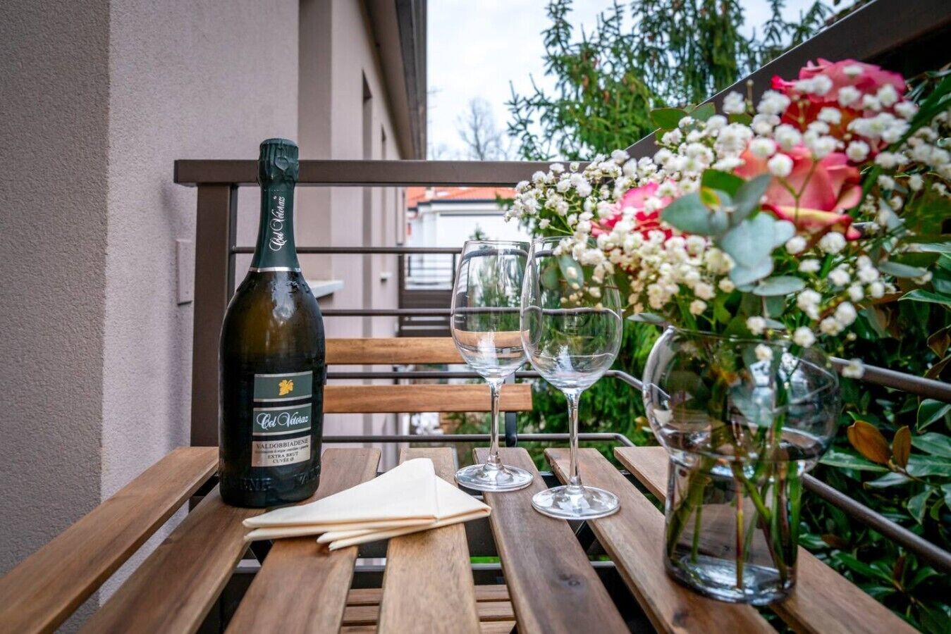 Une bouteille de vin, trois verres à vin, une serviette et un vase rempli de fleurs, le tout posé sur une table en bois.