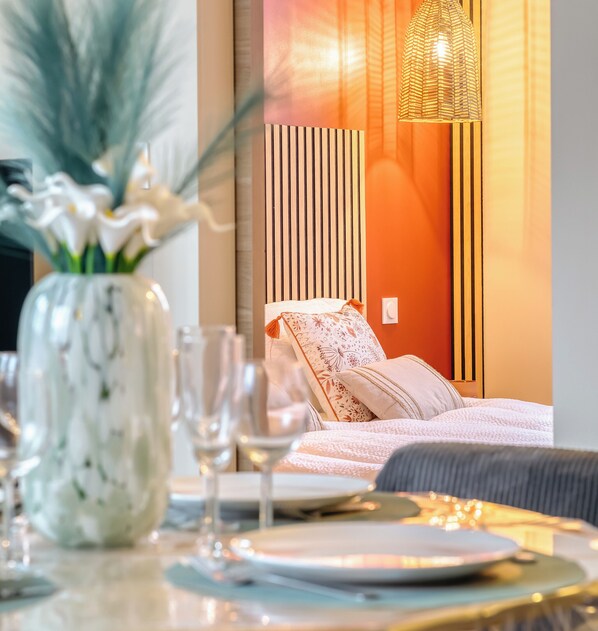 A modern bedroom with a bed, bedside table, and a vase of flowers.