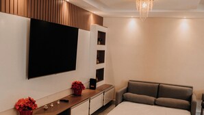 Een moderne woonkamer met een flatscreen televisie, een bank, een salontafel en een tv-meubel met decoratieve objecten.
