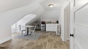 Een kleine keuken met een eethoek, witte kasten en een kleine koelkast.