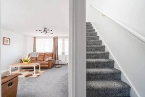 Un salon moderne avec un canapé en cuir marron, une table basse et un lustre.