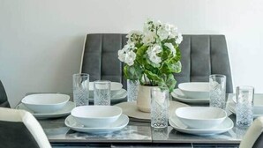 Une table à manger dressée avec des assiettes, des verres et un vase de fleurs.