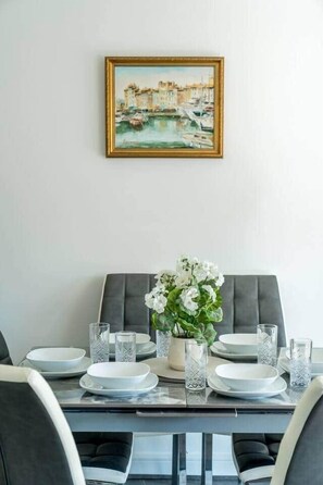 Een eettafel gedekt met borden, glazen en een vaas met bloemen.