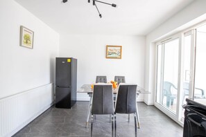 Een moderne keuken met een eettafel, stoelen, een koelkast en een groot raam.