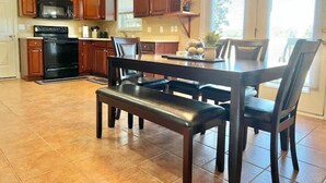Una cocina con armarios de madera, una estufa negra y una mesa de comedor con sillas.