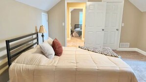 Un dormitorio con una cama, una lámpara y una puerta que da a otra habitación.