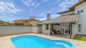 Propiedad residencial con piscina, patio y zona de estar cubierta al aire libre.