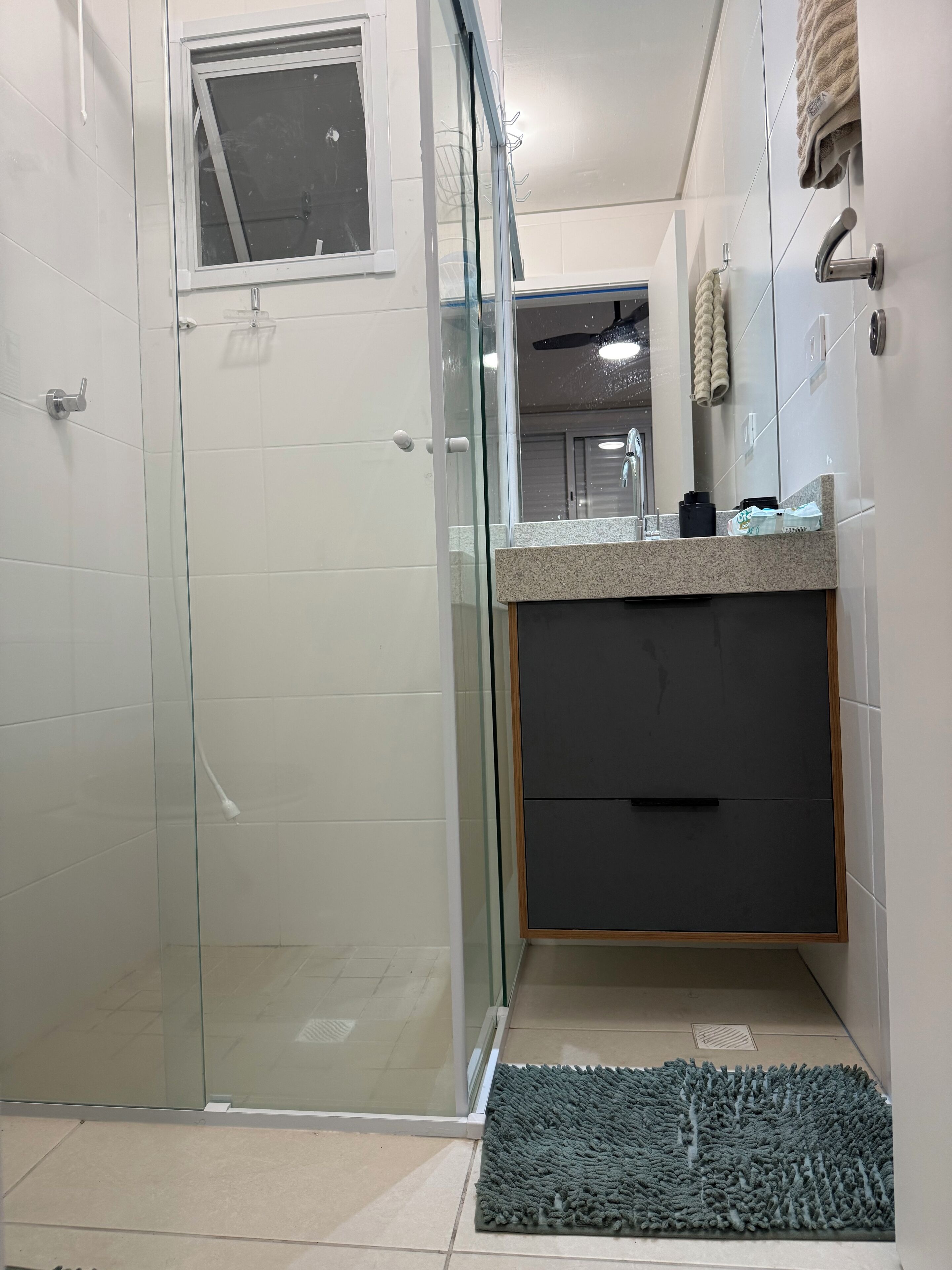 A modern bathroom with a glass shower enclosure, a vanity with a dark cabinet, and a towel rack.