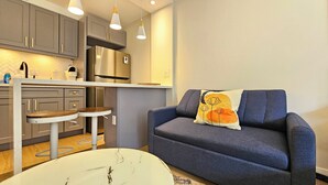 A modern kitchen with grey cabinets, a stainless steel refrigerator, and pendant lighting. - Stunning Studio w/Pool & Includes Free Dedicated Parking Space (Honolulu)